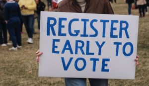 Person holding a register early to vote sign